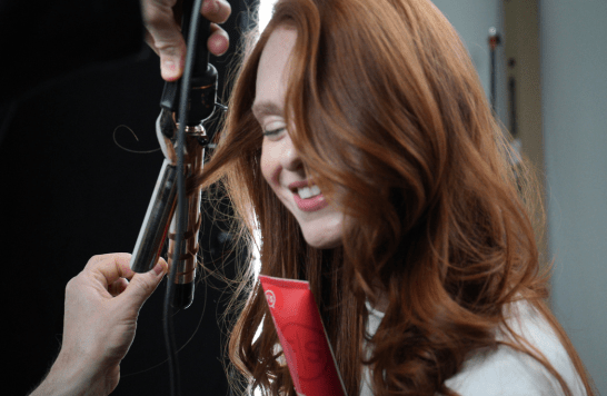 Stylist curling model hair on set